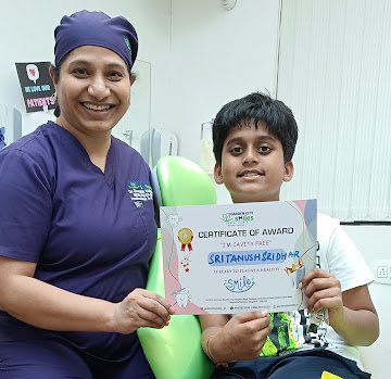 A child holding a certificate beside a clinician