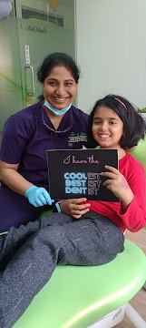 A child and clinician with a Coolest Dentist sign