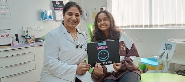 A visitor and clinician holding a smile sign in the treatment room